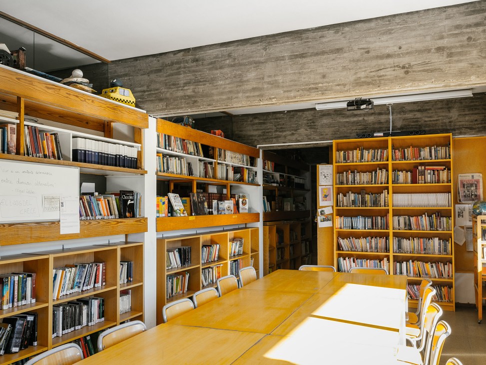 One of Colegio Estudio's five libraries with wooden shelving, books, study tables, and concrete ceiling beams.