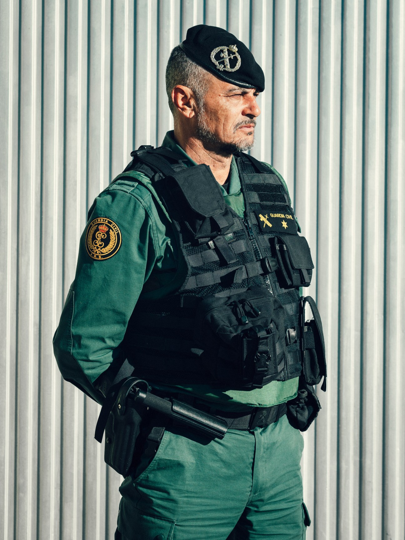 Guardia Civil officer in green uniform and black tactical vest wearing traditional tricornio hat.