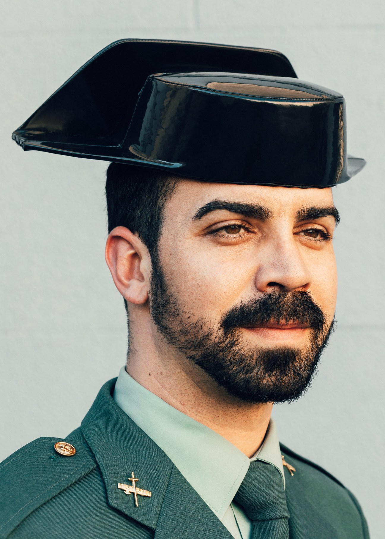 Guardia Civil officer wearing distinctive black tricornio hat and green uniform with cross insignia.