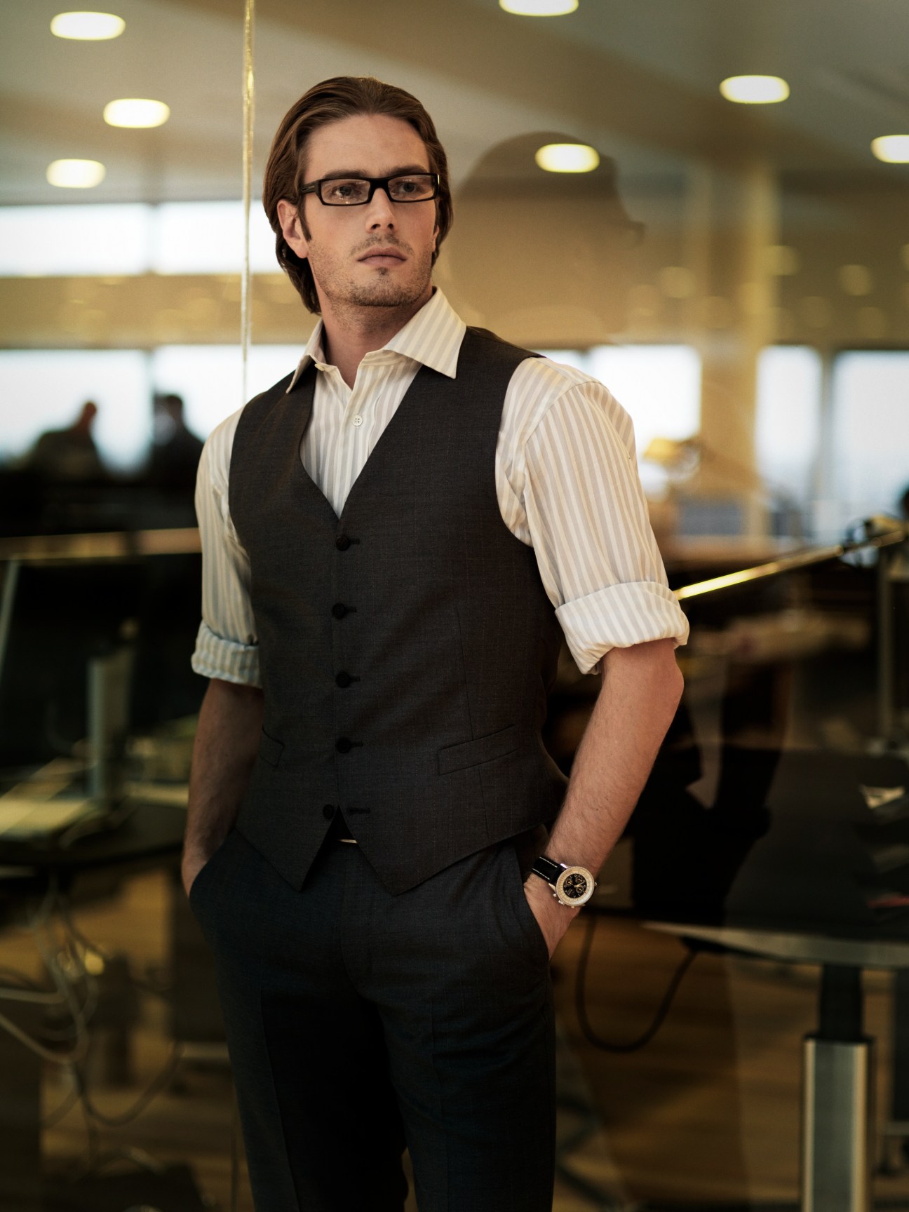 Man wearing Dunhill cotton shirt and waistcoat with Prada glasses in modern office setting.