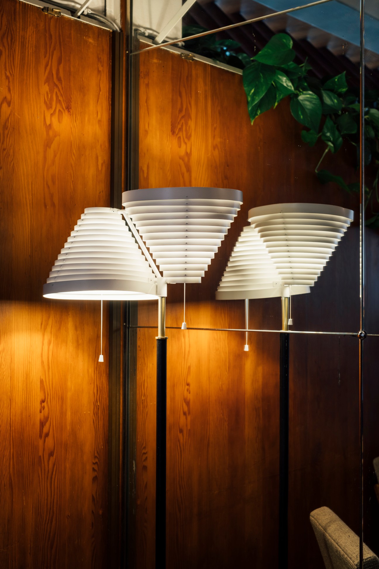 Three white layered pendant lamps hanging in front of wood paneled walls