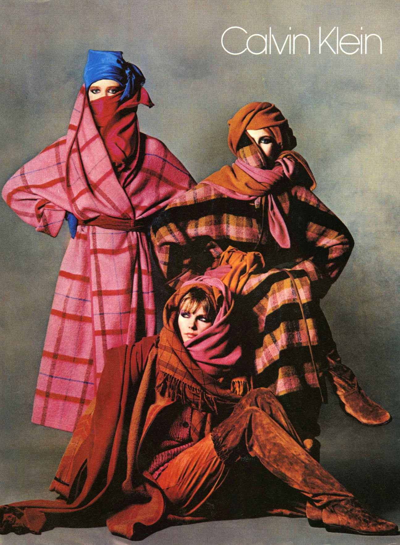 Calvin Klein 1980s advertisement featuring three models in bold plaid and colorful draped fabrics with head coverings.