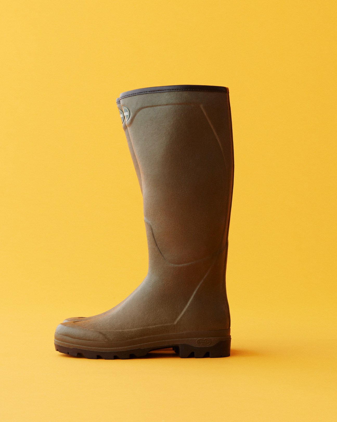 Brown Le Chameau rain boot against a bright yellow background