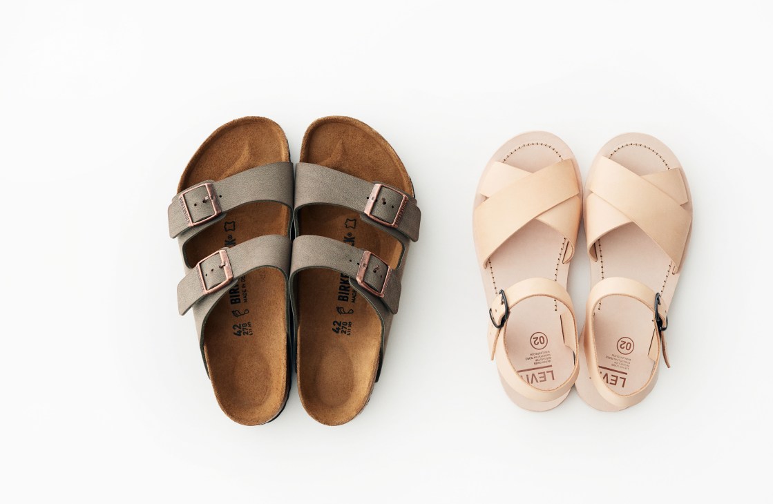 Overhead view of two sandals: Birkenstock with brown suede and gray straps on left, cream leather Levit 02 on right.