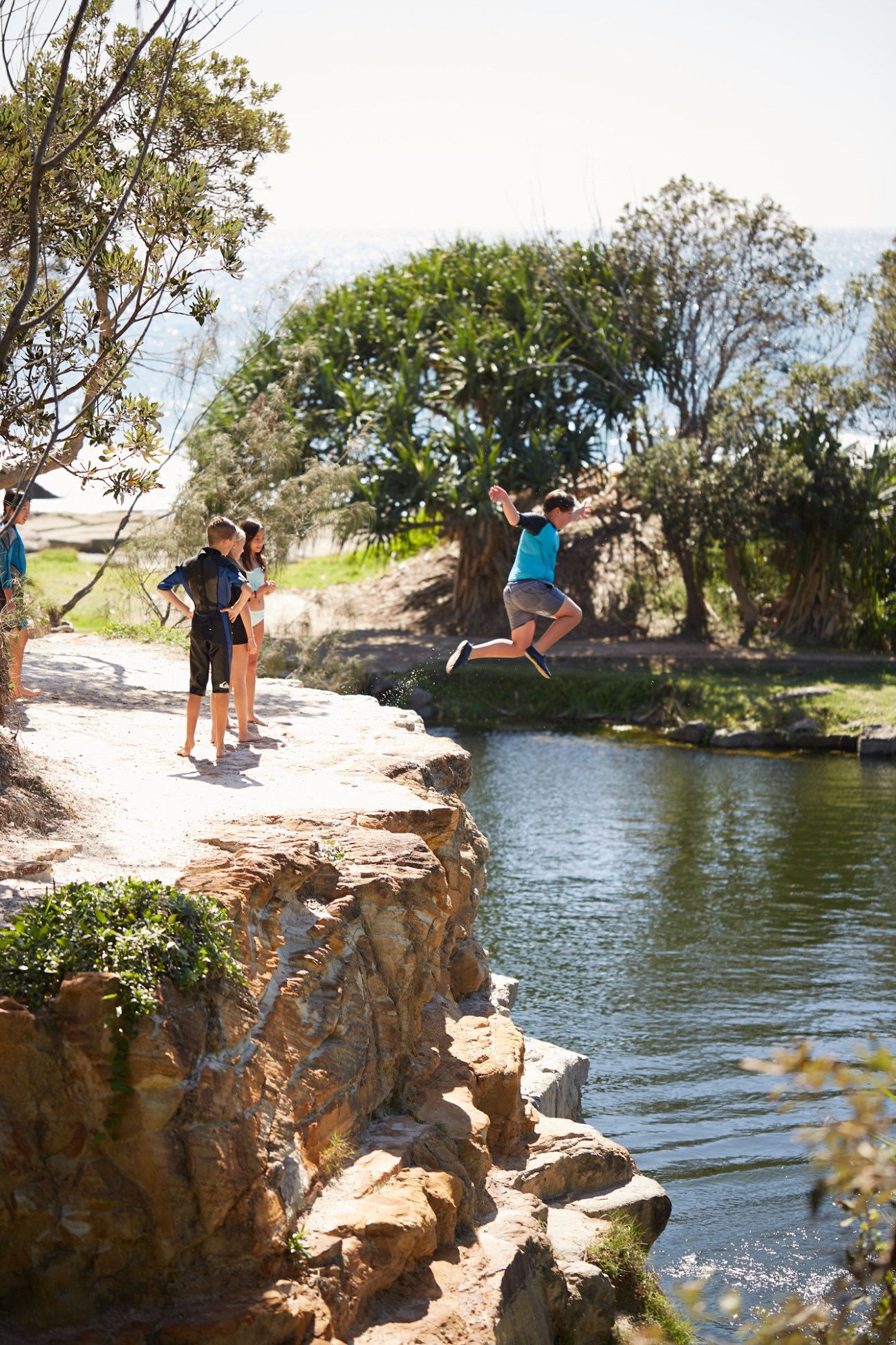 Children jumping off rocks into Angourie's Blue Pool, a former quarry site filled with freshwater.