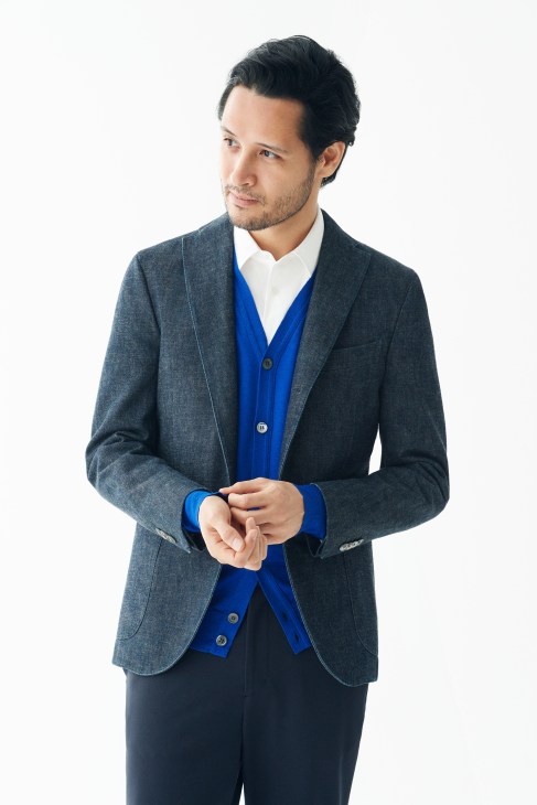 Man wearing a gray Boglioli jacket, blue John Smedley cardigan, white Itty-Bitty shirt, and Yaeca trousers.