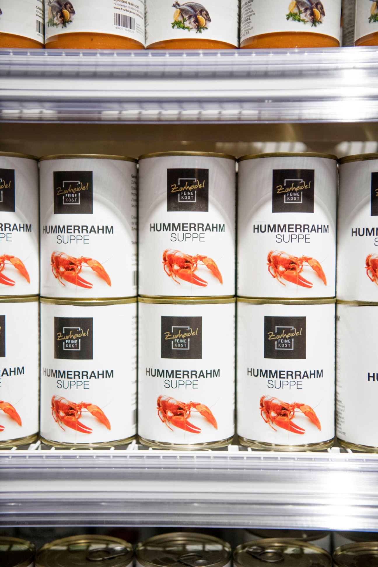 Cans of Hummerrahm lobster soup stacked on shelves at Zurheide supermarket.