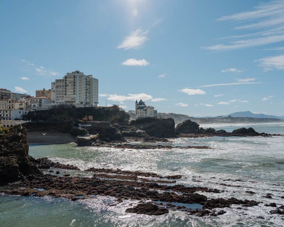 Coastal town of Biarritz with belle époque architecture, rocky shores and Atlantic waves under blue sky.