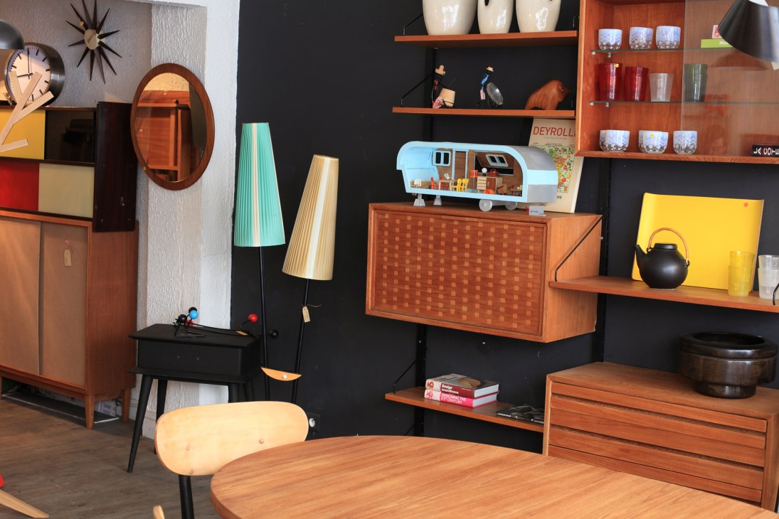 Mobilhome furniture shop interior displaying vintage 1950s and 60s-style wooden furniture, lamps, and decorative items.