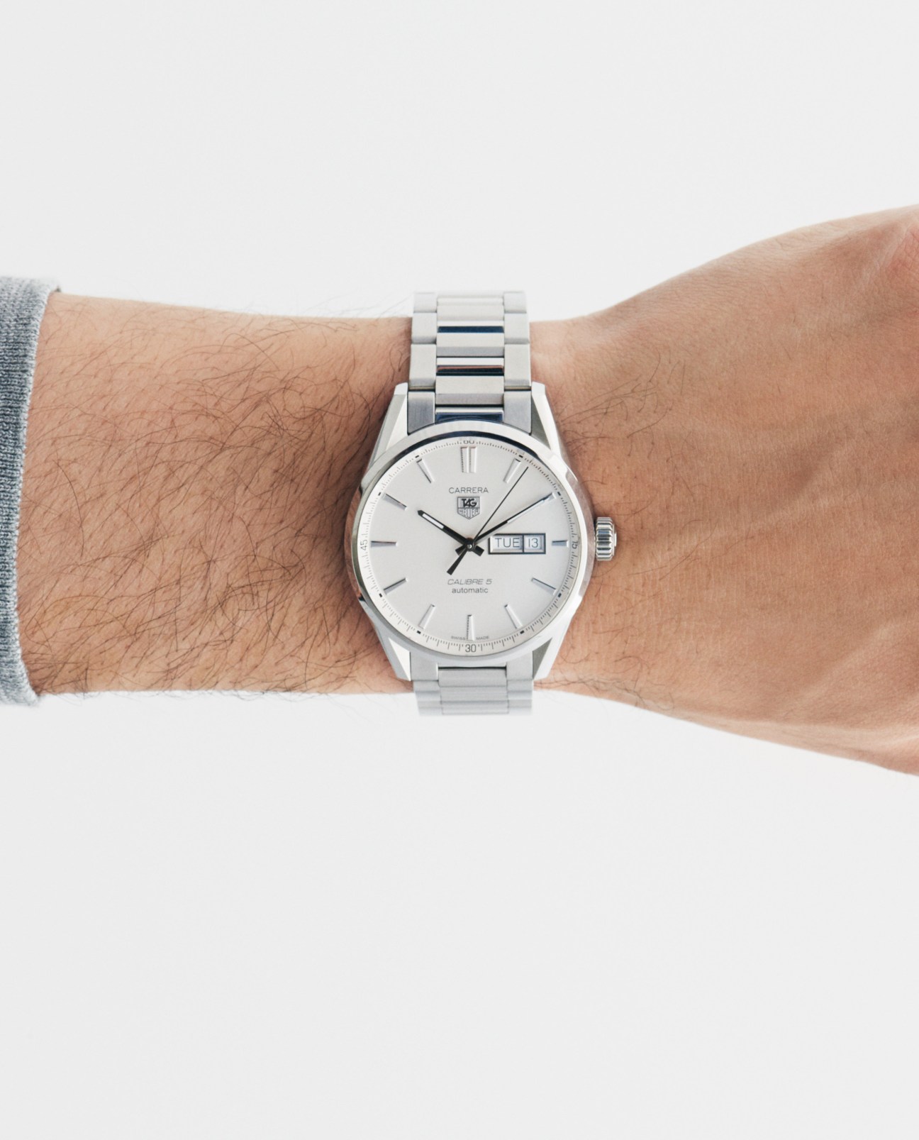 Tag Heuer Carrera watch with silver metal bracelet and white dial on wrist.