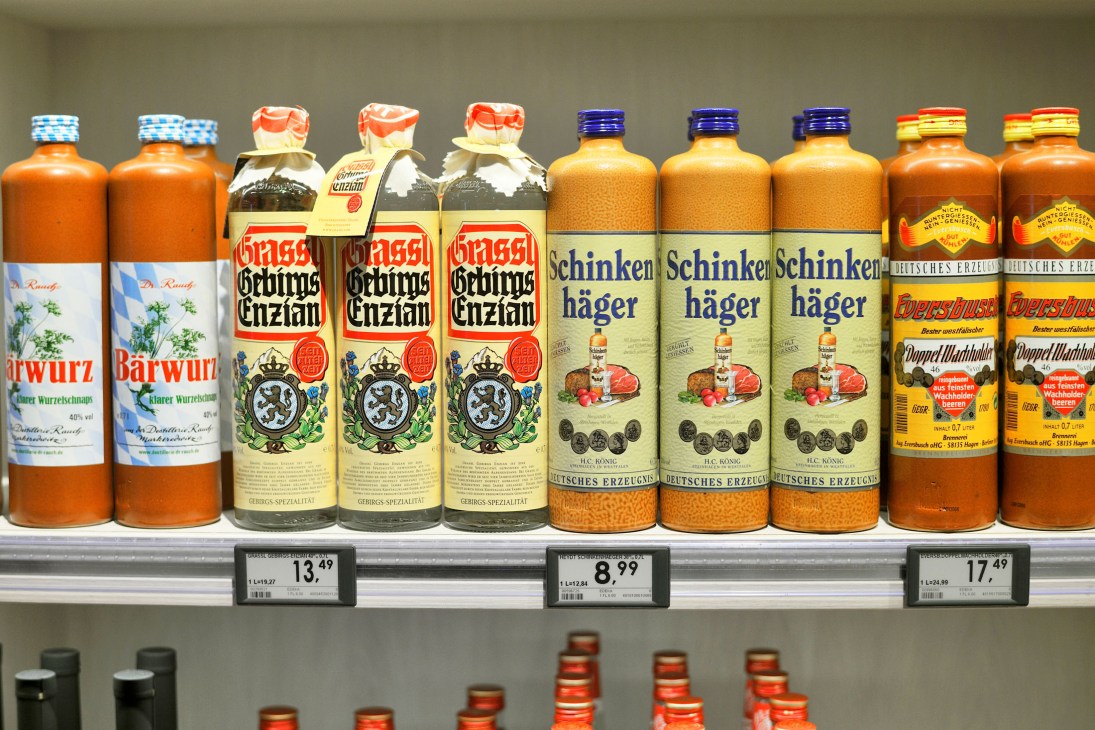 Bottles of German spirits and liqueurs displayed on white shelf with price labels