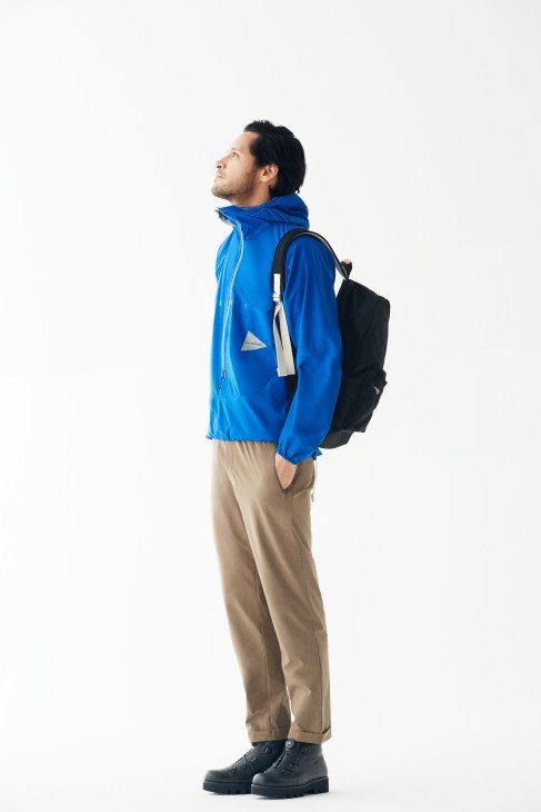 Man wearing blue jacket, beige trousers, black boots and Porter backpack.