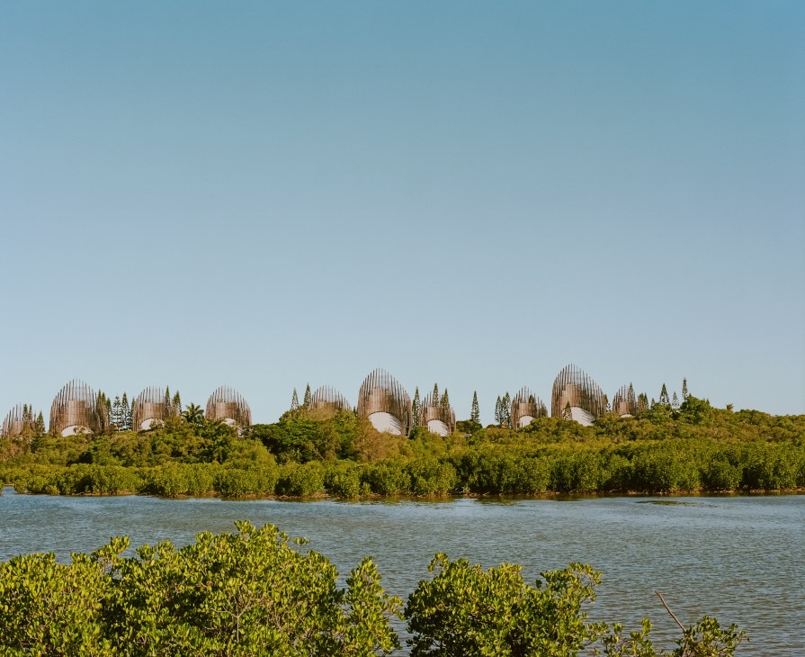 Tjibaou Cultural Centre's distinctive shell-shaped structures designed by Renzo Piano, viewed across water with mangroves in foreground.
