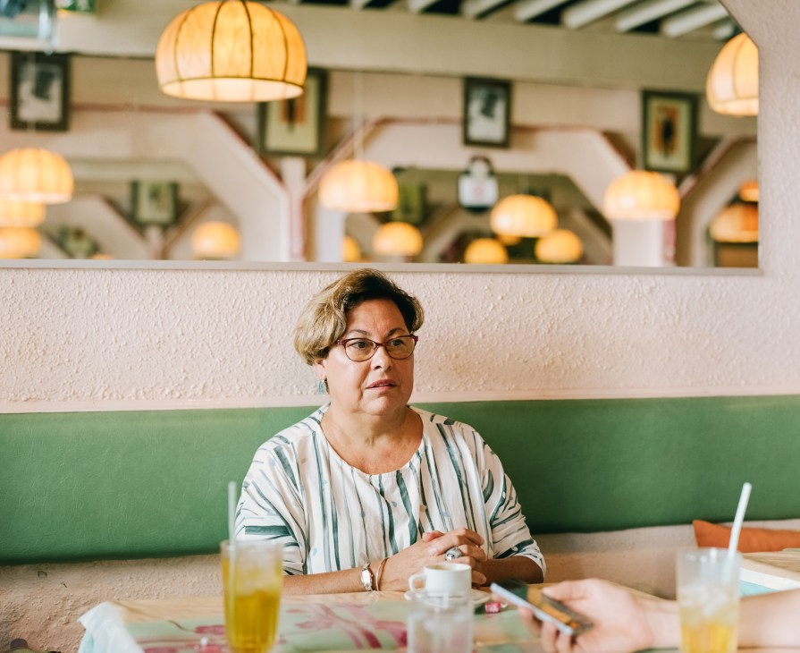 Bianca Henin, representative of Marine Le Pen's National Front, sitting at a table in a modern café with pendant lights.