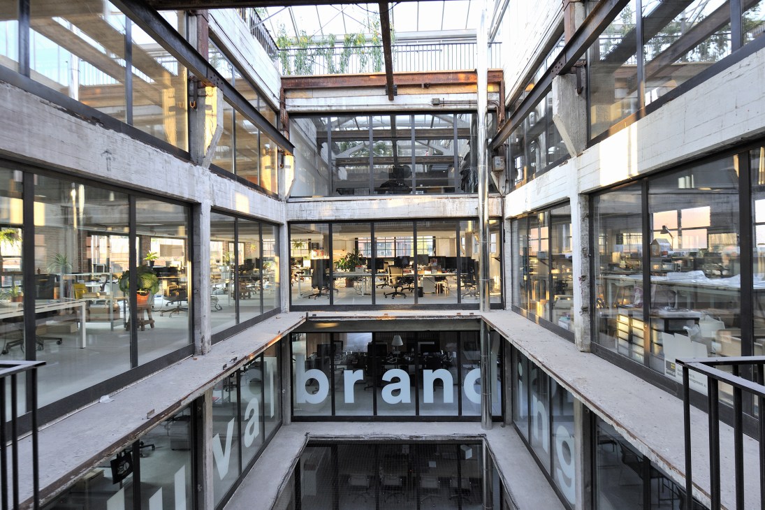Bright modern office space with large windows, exposed ceiling beams, and contemporary furniture in Pakt development.