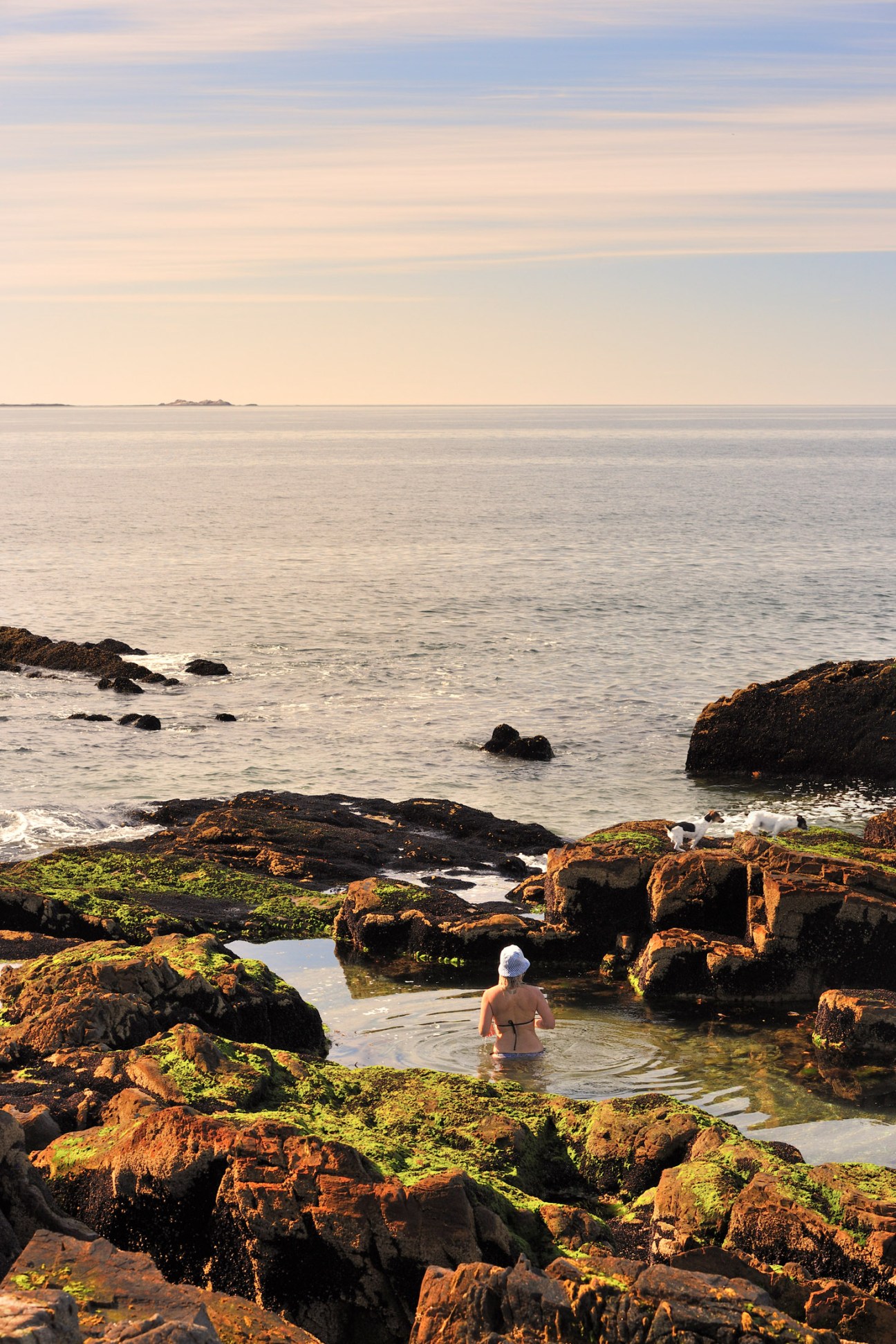 Person wading in a natural rock pool by the Patagonian coast at sunset.