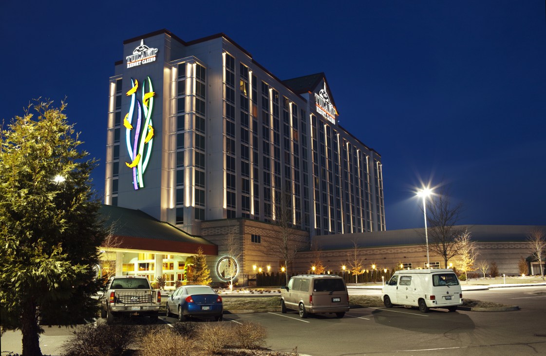 Illuminated Tulalip Casino hotel building at dusk with tribal logo signage and parking lot.