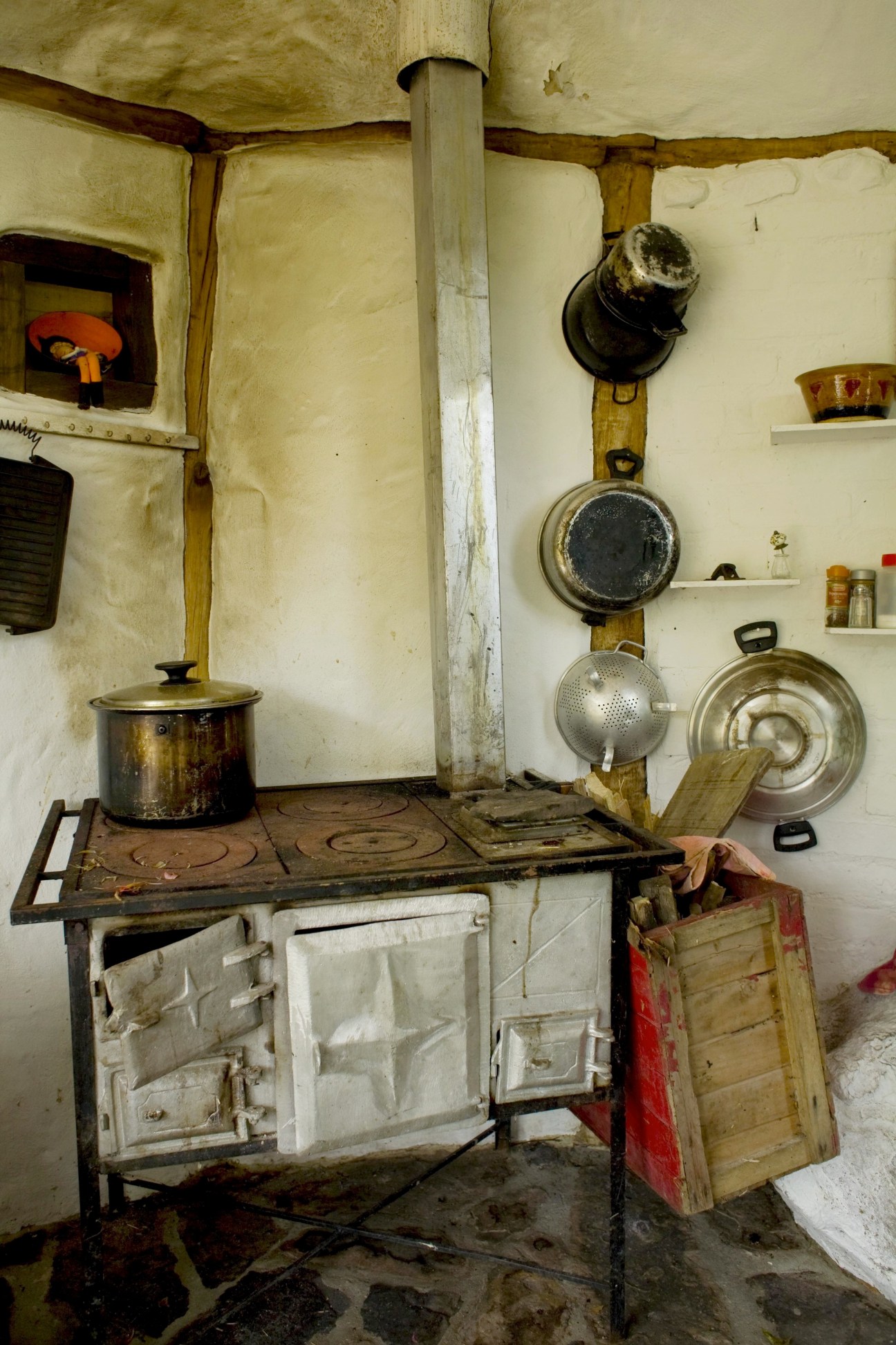 Rustic kitchen interior with old stove, pots and pans hanging on cream walls