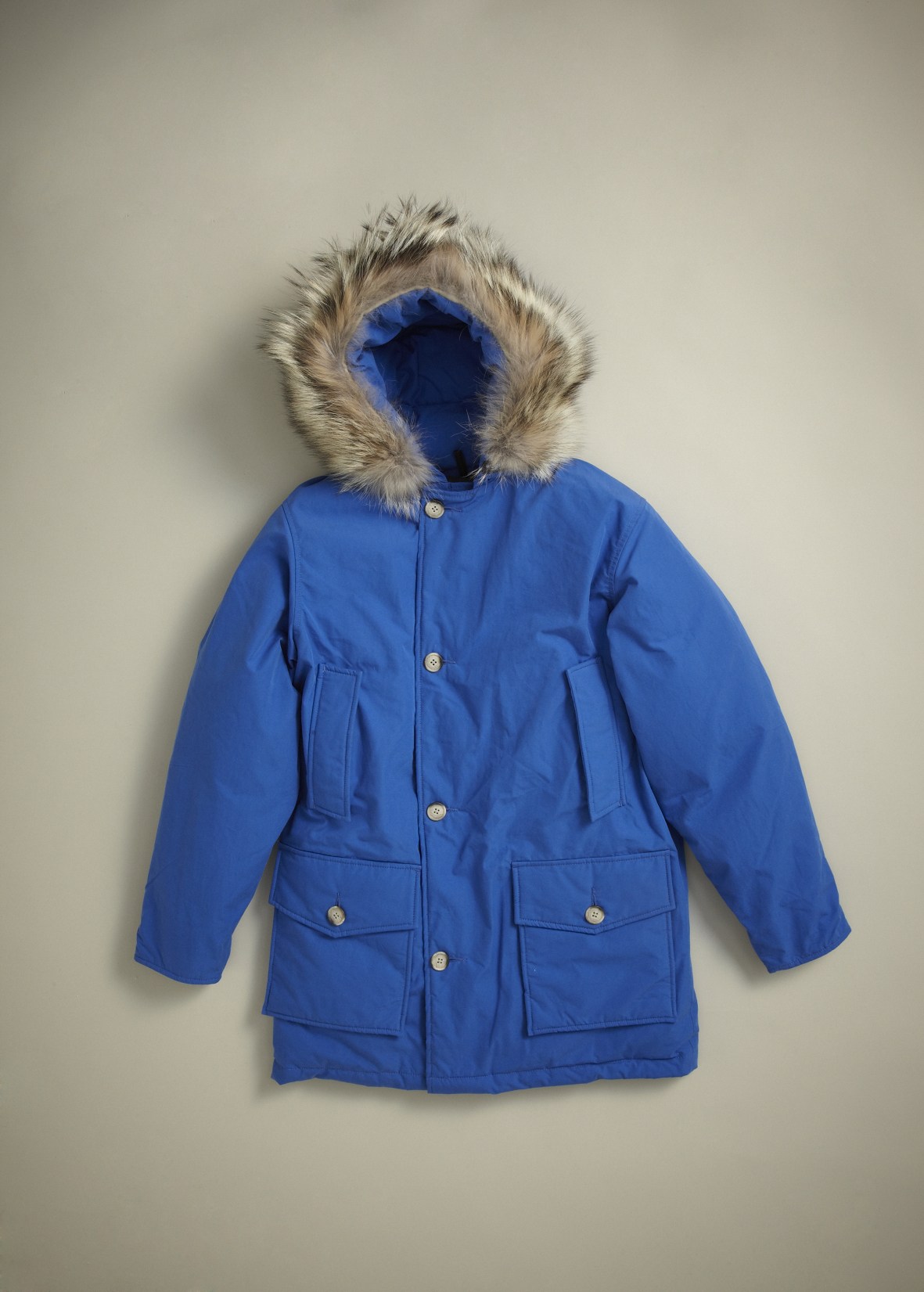 Royal blue Woolrich Arctic Parka with fur-lined hood and chest pockets displayed on neutral background.