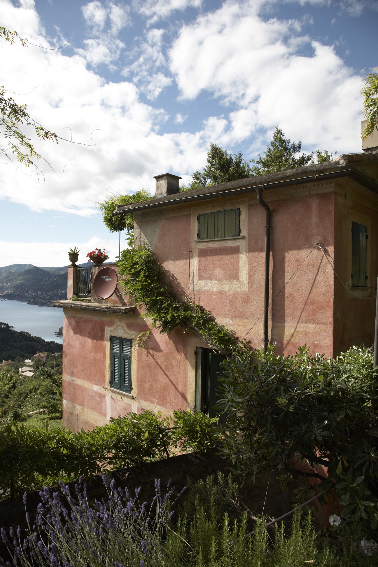 A restored pink mansion on Mount Portofino overlooking the Ligurian coast with Mediterranean gardens.