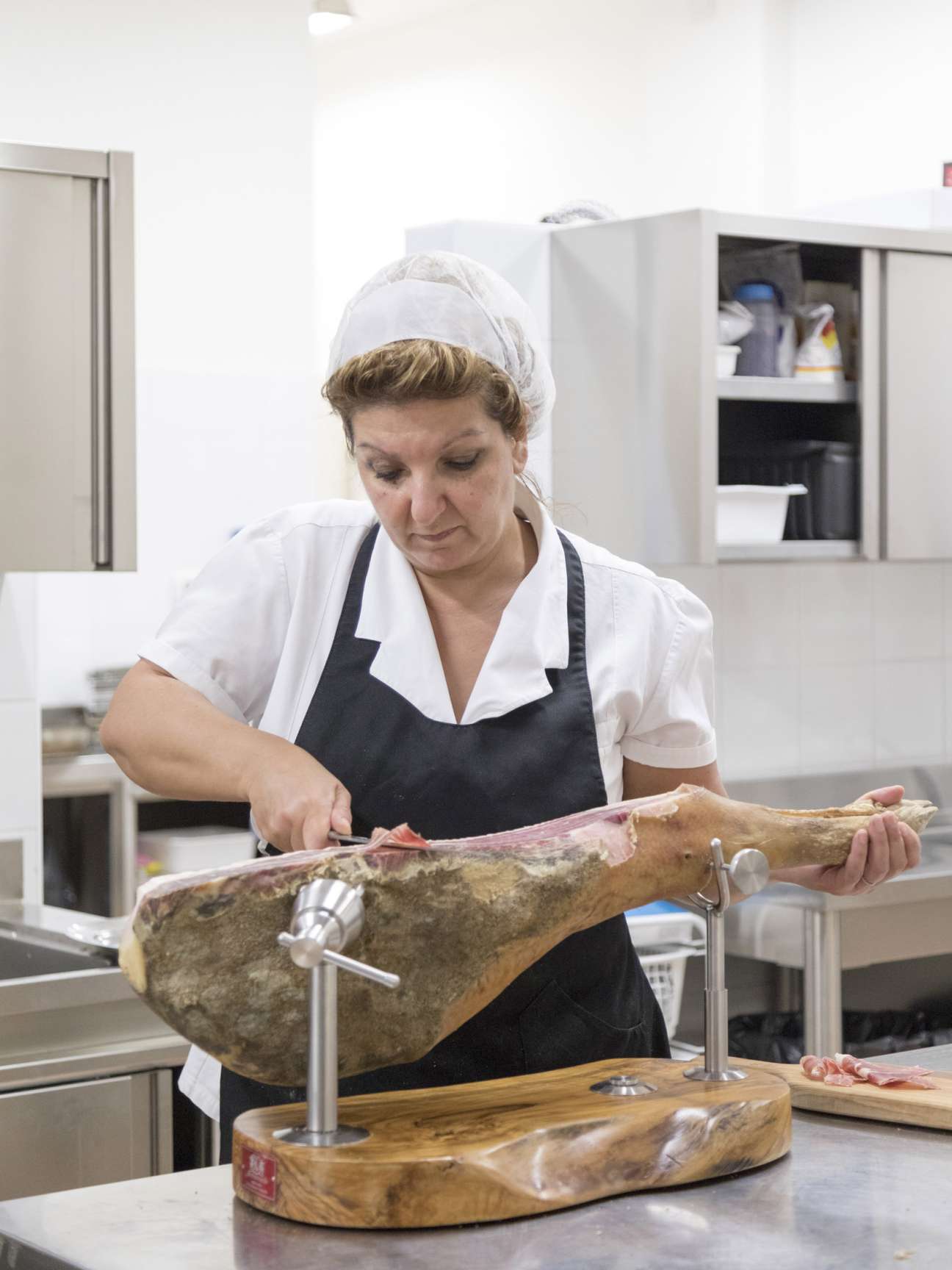 Chef carefully slicing prosciutto ham at Brunello Cucinelli's kitchen