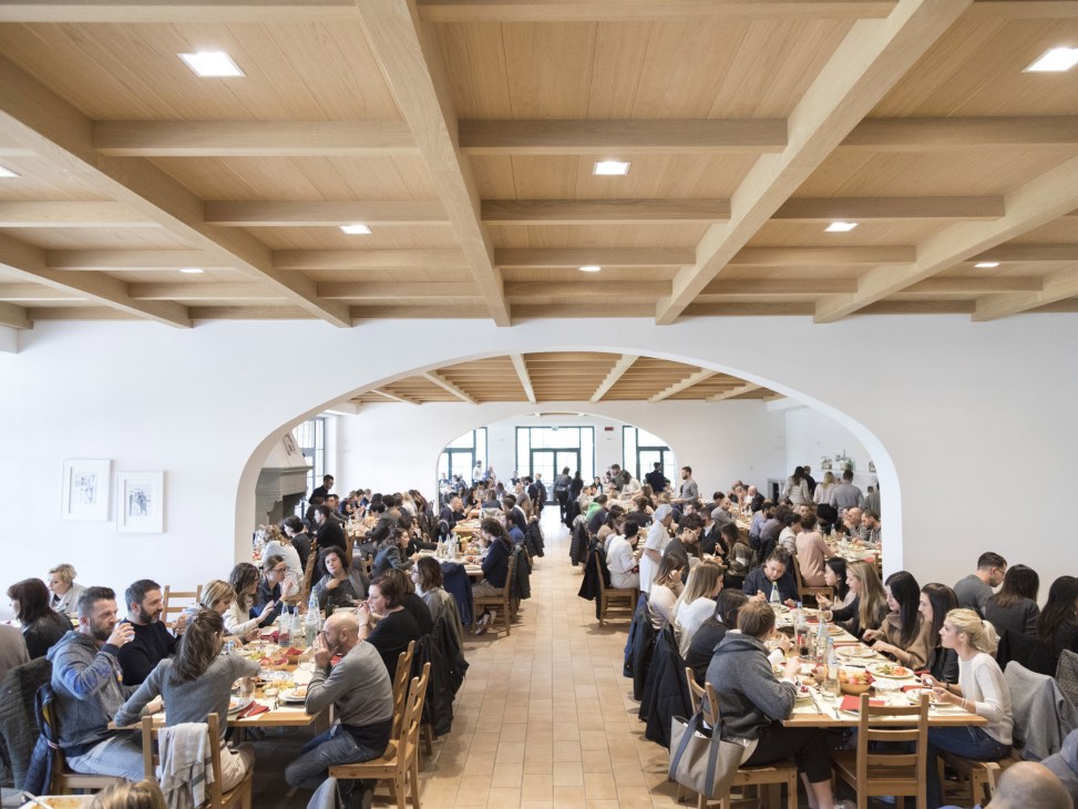 The elegant dining room at Brunello Cucinelli's company canteen with wooden tables and large windows