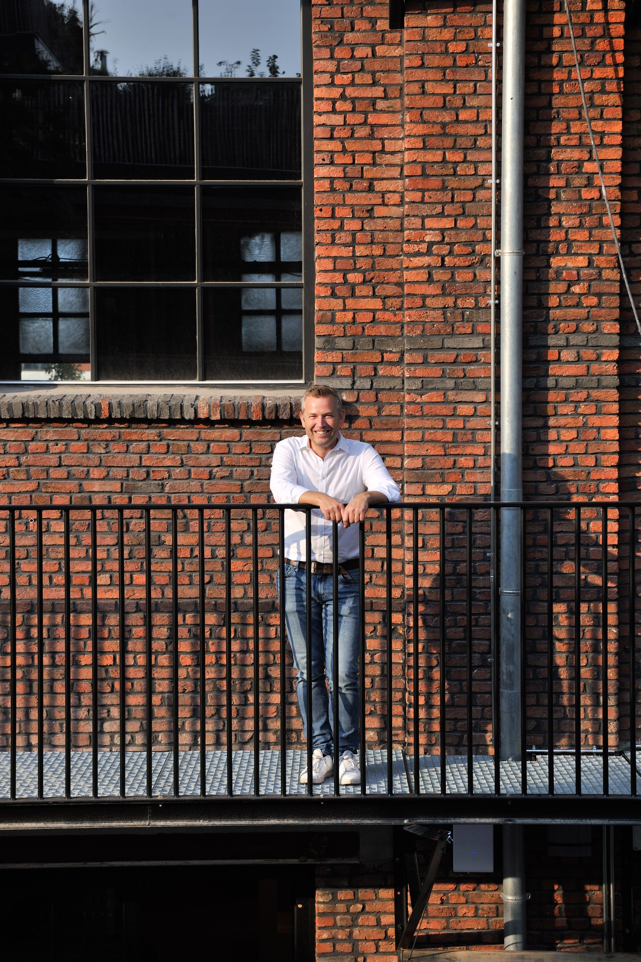 Stefan Bostoen standing against a red brick wall at the Pakt development in Antwerp