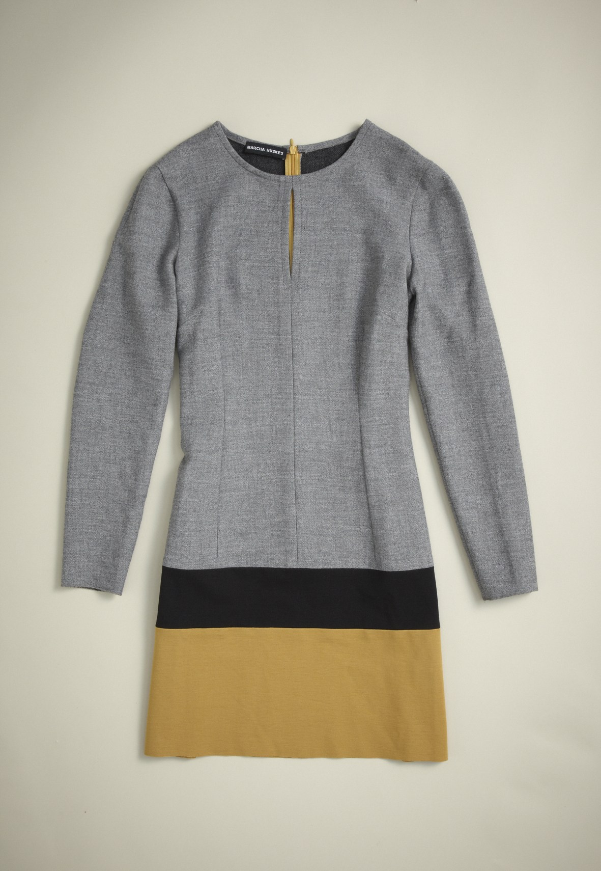 Gray long-sleeve dress with black and mustard-yellow colorblock hem by Marcha Hüskes.