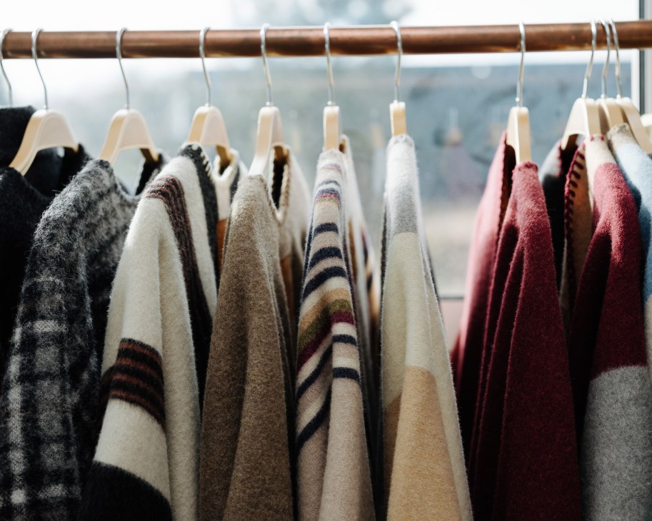 Wool capes and coats in neutral and burgundy tones hung on wooden hangers in La Méricaine's showroom.