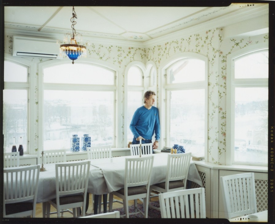 Rickard Halleröd stands at a dining table in Albert restaurant's bright, elegant dining room with panoramic windows overlooking Trollhättan.