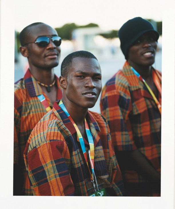 Three Mozambique athletes wearing orange and red plaid uniforms at the Lusophone Games opening ceremony.