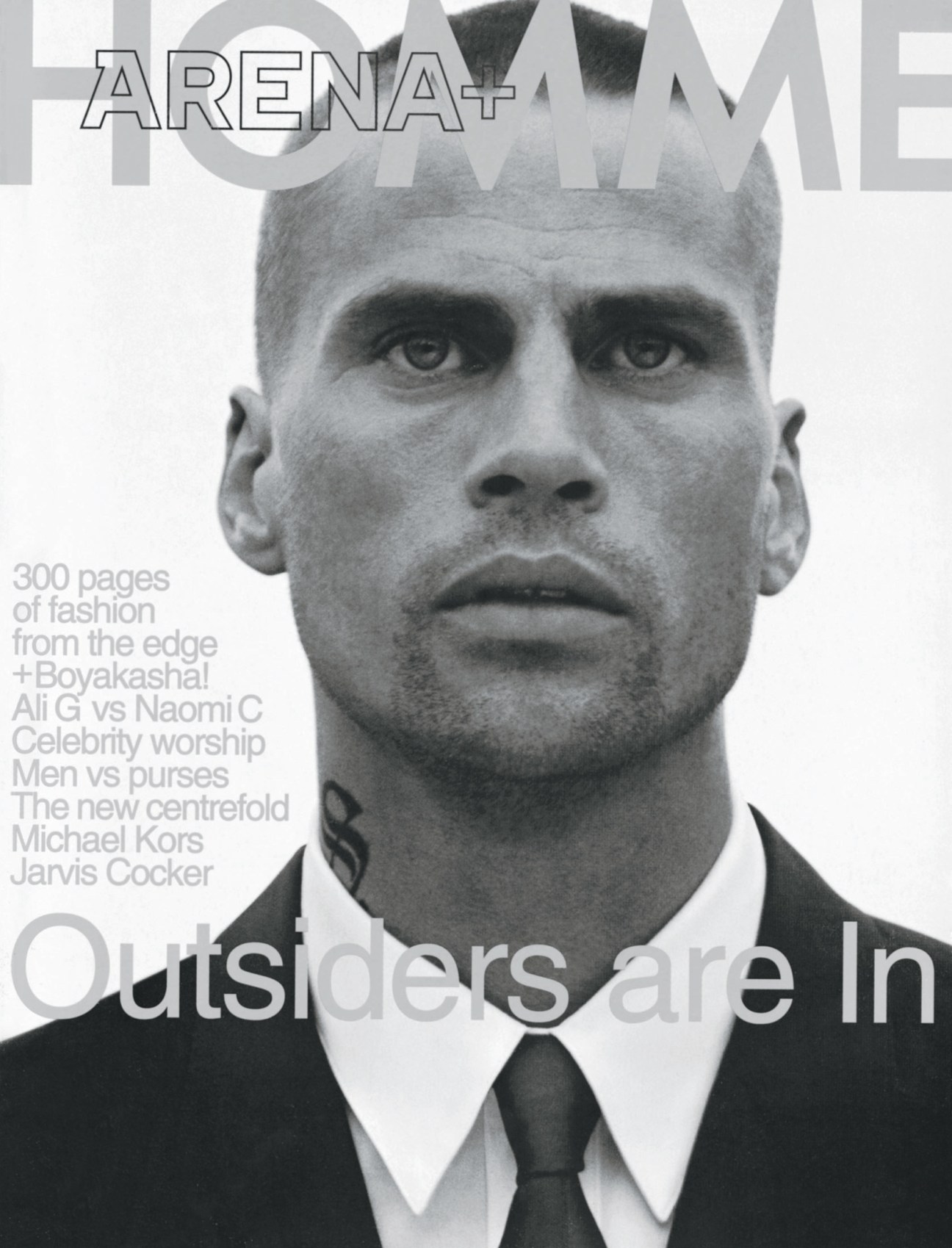 Black and white portrait of a man with styled hair wearing a dark suit and tie on an Arena Homme Plus magazine cover.