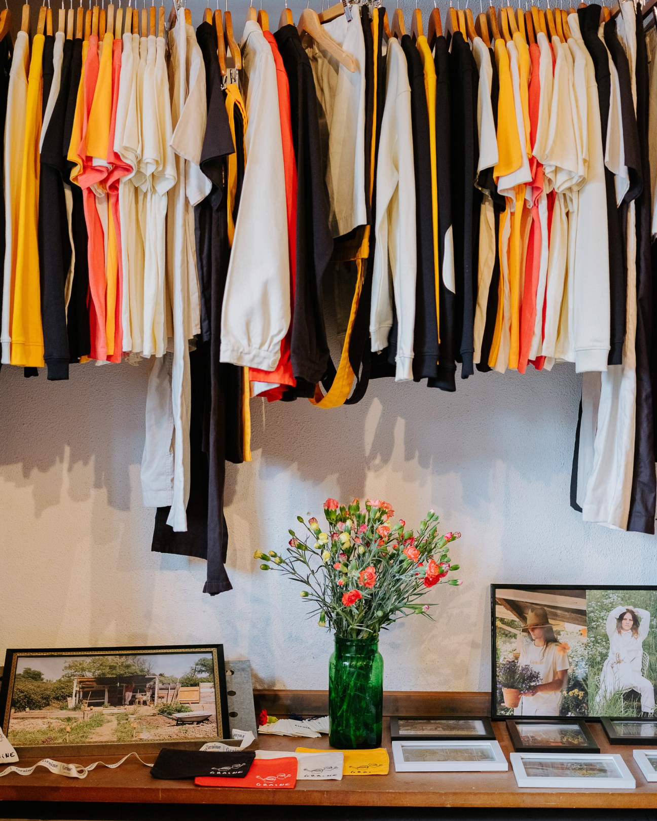 Colorful clothing hung on wooden hangers displaying Graine's debut collection in warm and neutral tones.