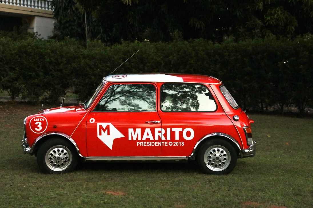 A red Mini Cooper car with white roof and MARITO campaign branding parked on grass.