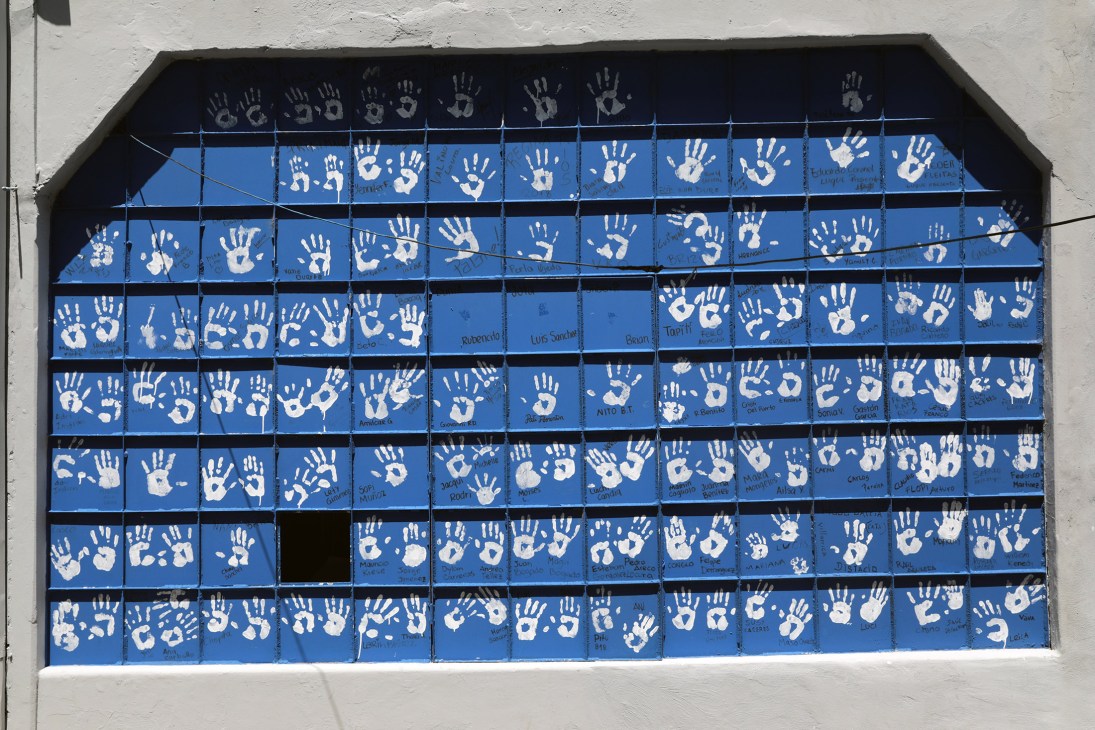 Blue garage door covered with white handprints and names as a memorial wall.