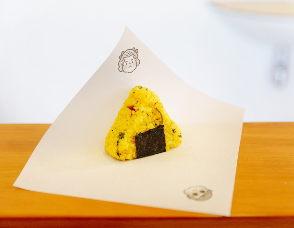 Yellow salted onigiri with nori seaweed on branded paper wrapper
