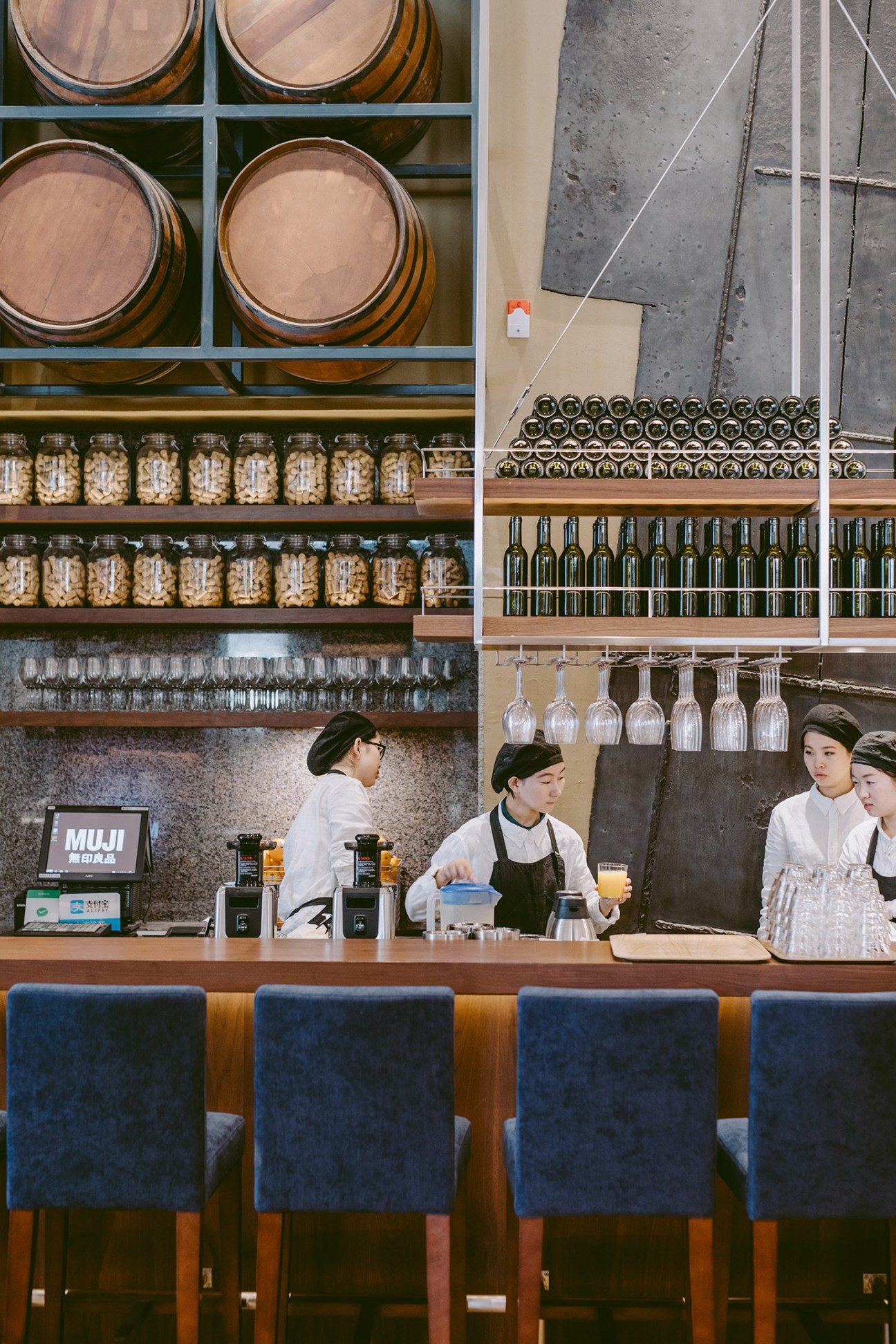 Muji Hotel bar in Shenzhen with staff behind counter, wooden barrels, bottles, and glasses on shelves above.