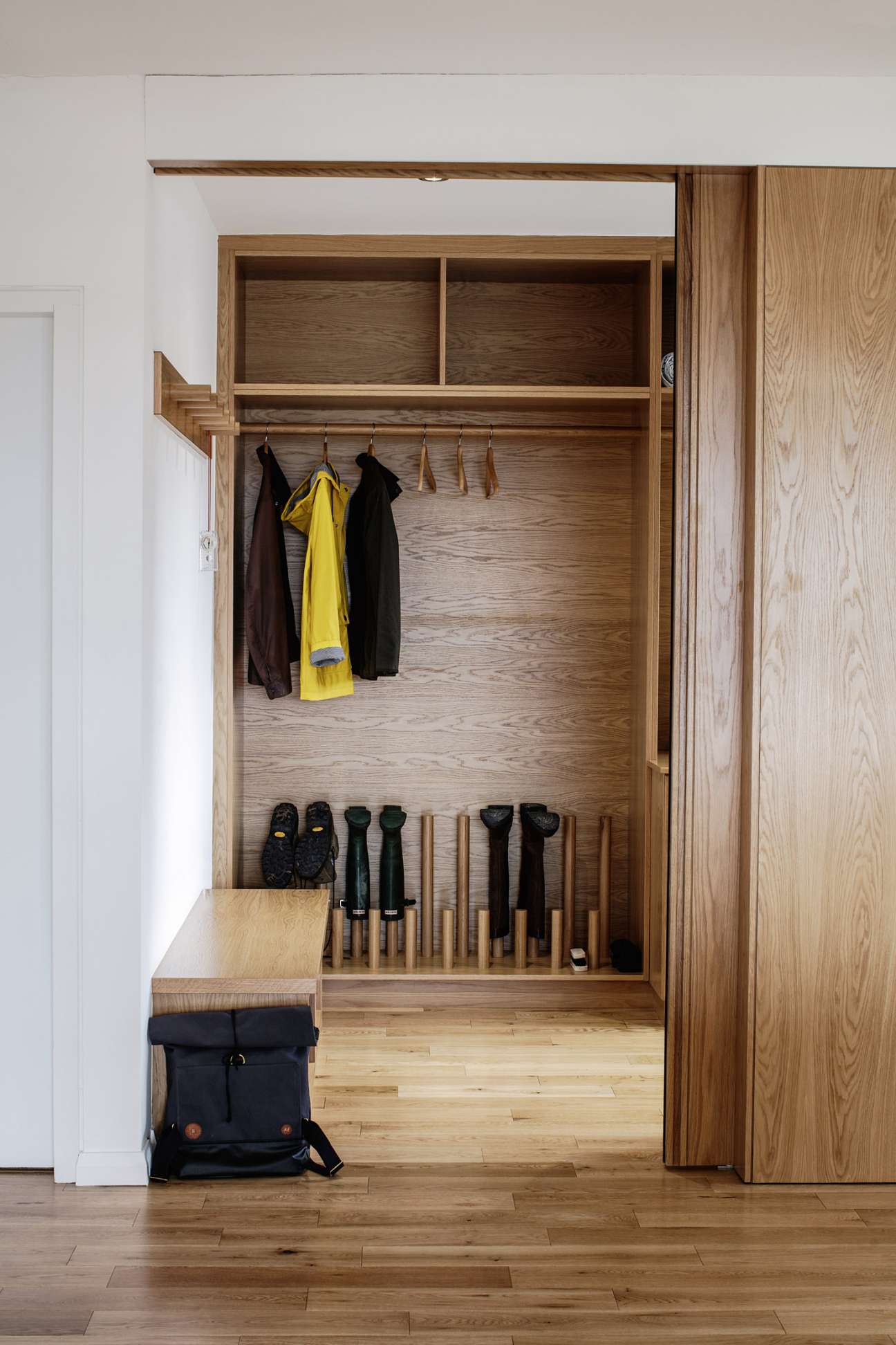 Wooden entryway closet with shelving storing hiking boots, jackets, and accessories at Breac House.