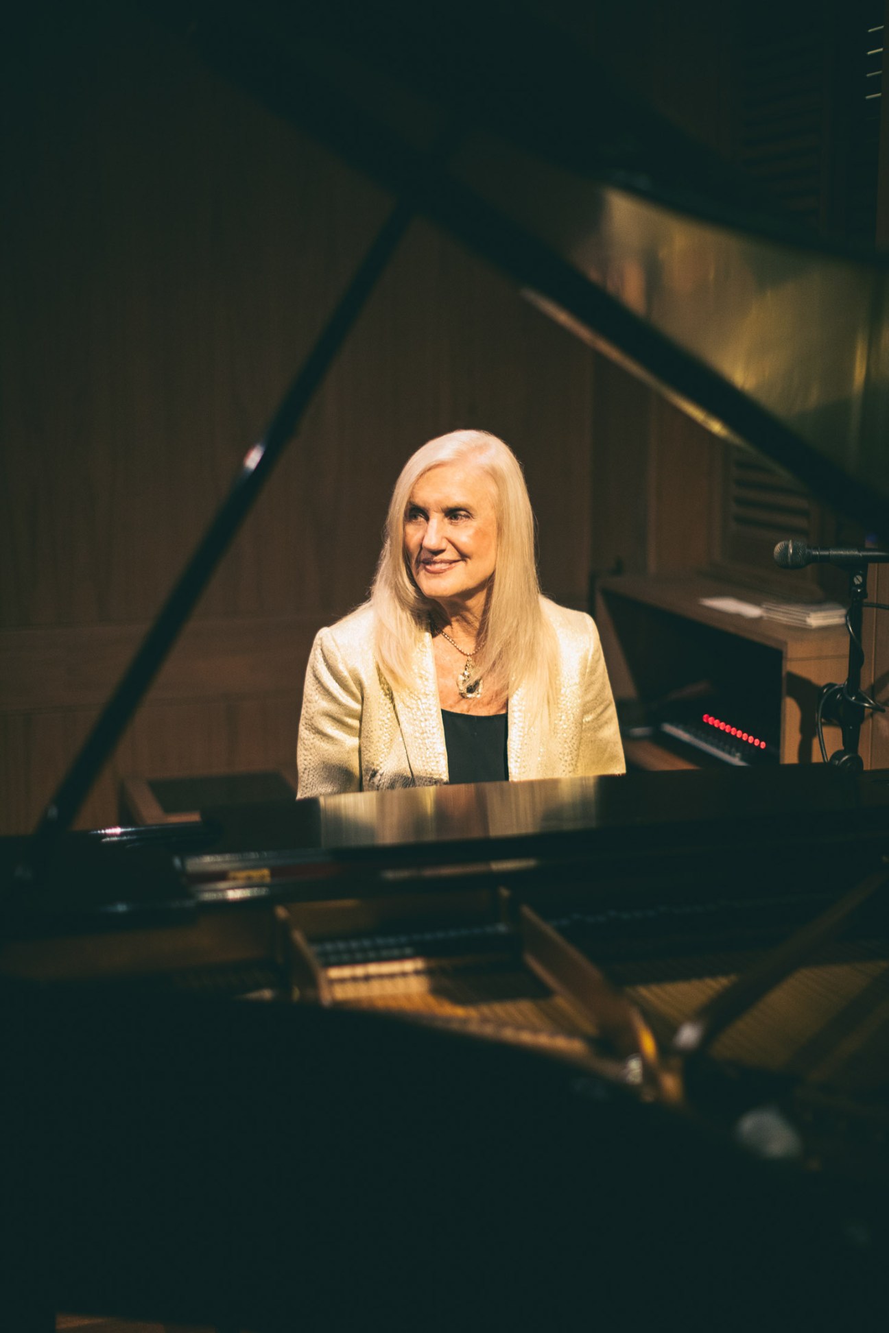 Maggie Herron seated at a Steinway grand piano in dimly lit Lewers Lounge, Honolulu.