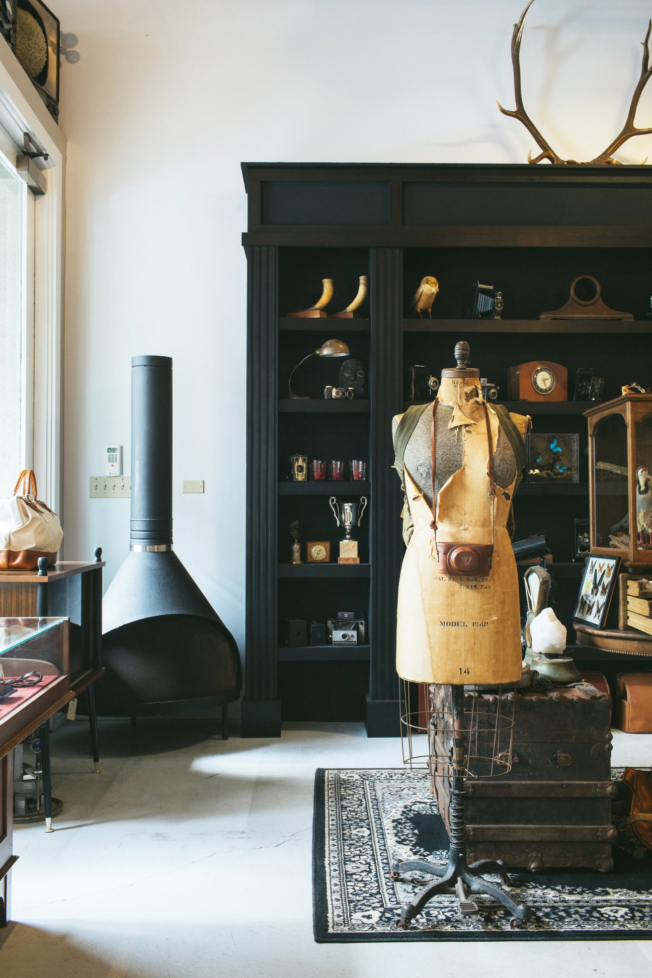 Interior of Hound and Quail shop displaying vintage furniture, taxidermy, and collectibles including a dress form and dark cabinet.