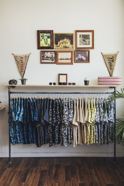 Saturdays NYC Crosby Street shop displaying patterned garments on a rack beneath a shelf with vintage framed photographs and decorative items.