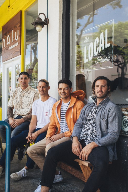 Four men pose outside Saturdays NYC storefront with yellow trim and signage visible behind them.