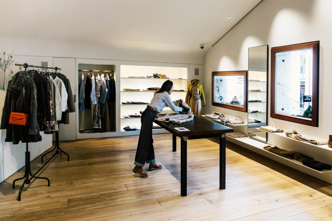 Woman browsing clothing in upstairs retail space at Frauenschuh store with wooden floors and display tables