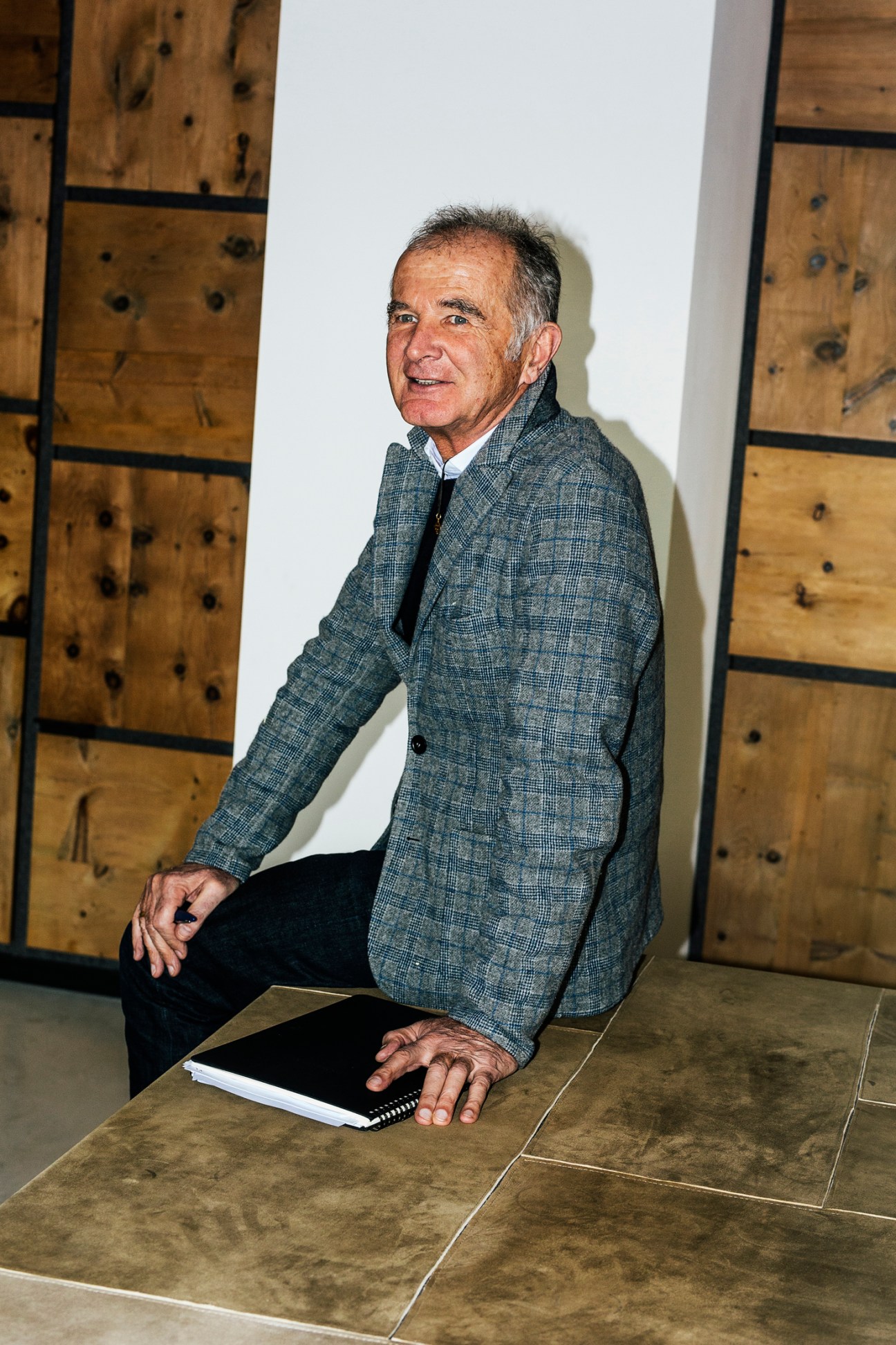 CEO Kaspar Frauenschuh sits on wooden desk in grey textured blazer at company office