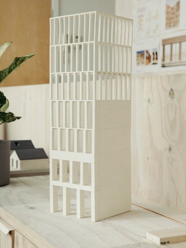 White architectural model of a tall tower building displayed in a studio setting