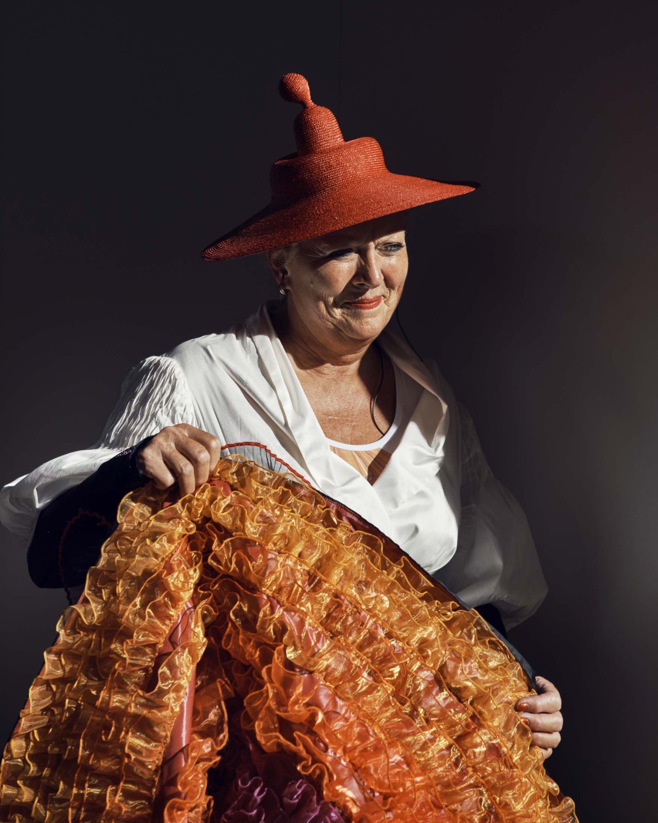 Performer in elaborate period dress with flowing textured skirt and red pointed hat