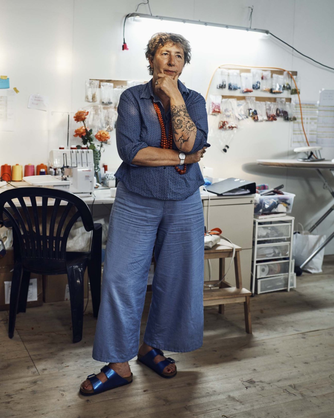 Giovanna Buzzi, head costumier, in her atelier wearing blue clothing with visible tattoos on her arm.