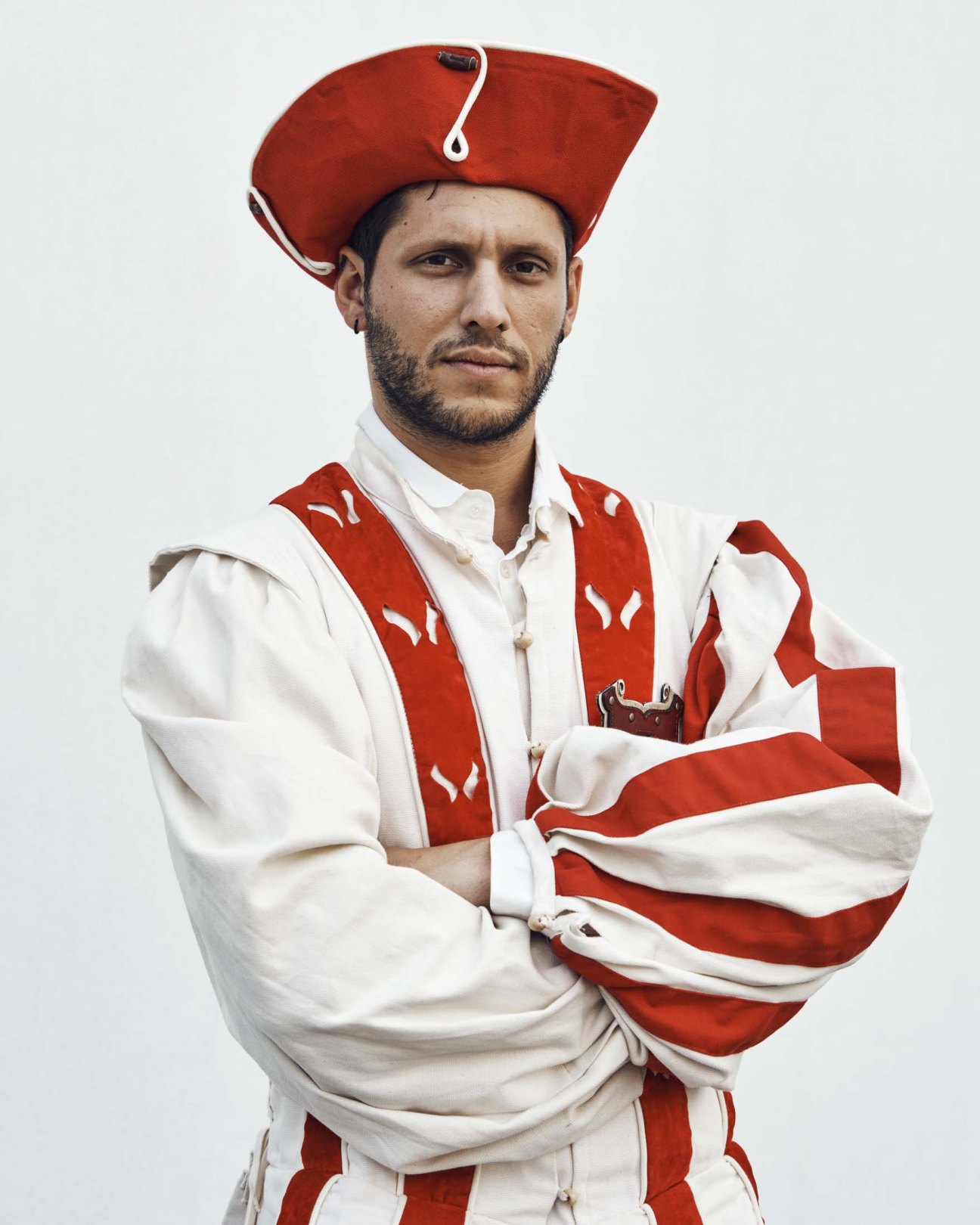 Man in red and white Swiss Guard uniform with bicorne hat against white background