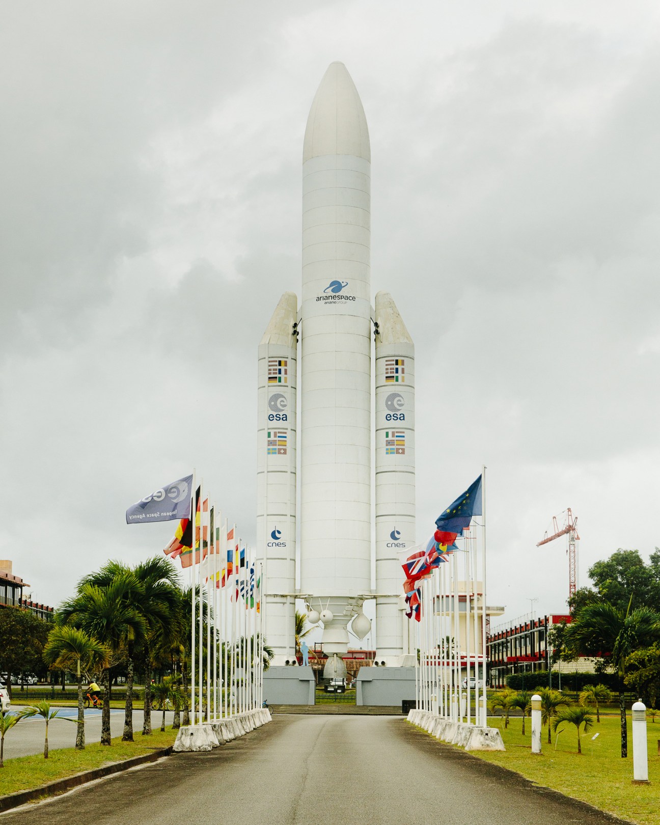 The Ariane rocket on display at Kourou Space Centre with international flags and palm trees.