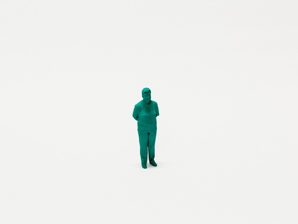 A 3D-printed turquoise figure of a woman standing against a plain background.